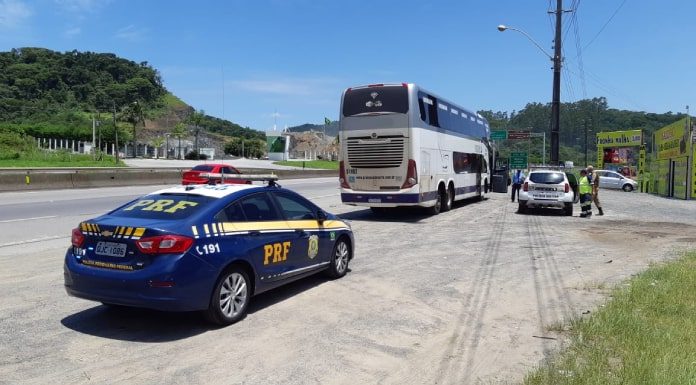 Passageiro é preso porque tentava fotografar e filmar mulher em ônibus - viatura da prf estacionada atrás do ônibus em beira de rodovia