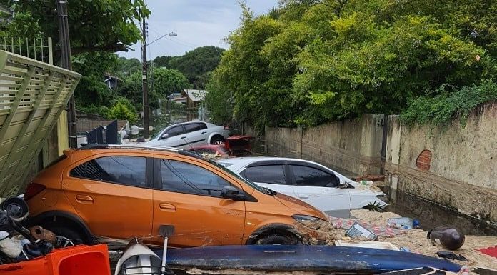 Lagoa artificial rompe - foto mostra carros empilhados em servidão alagada com espuma e diversos objetos boiando