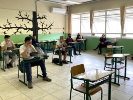 calendário escolar estadual - alunos sentados em carteiras separadas usando máscara dentro de sala de aula
