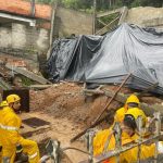 homens de equipe de emergência em área de casa desabada com lona por cima de parte da estrutura; florianópolis decretou situação de emergência