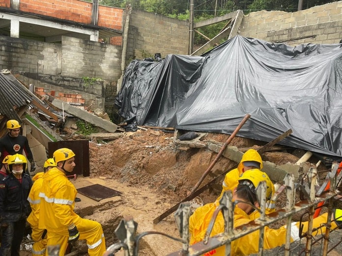 homens de equipe de emergência em área de casa desabada com lona por cima de parte da estrutura; florianópolis decretou situação de emergência