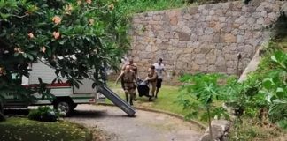 Polícia mata: policias carregando saco com corpo de um dos ladrões mortos na ponta de baixo para uma viatura do iml