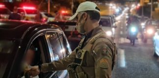 policial militar usa máscara e faz teste de bafômetro em motorista; grande trânsito ao fundo - motoristas foram flagrados embriagados