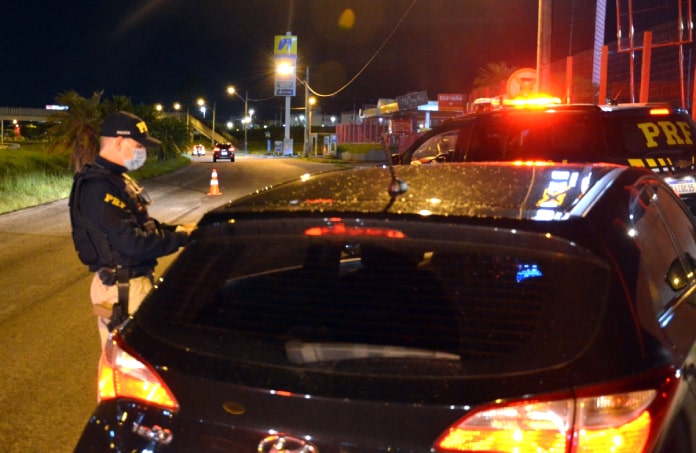 policial rodoviário federal faz teste de bafômetro em alguém dentro de um veículo hyundai