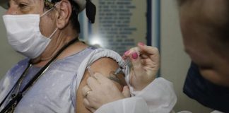 idosa usando máscara recebe dose de vacina no braço - vacinação de idosos acima de 75 anos