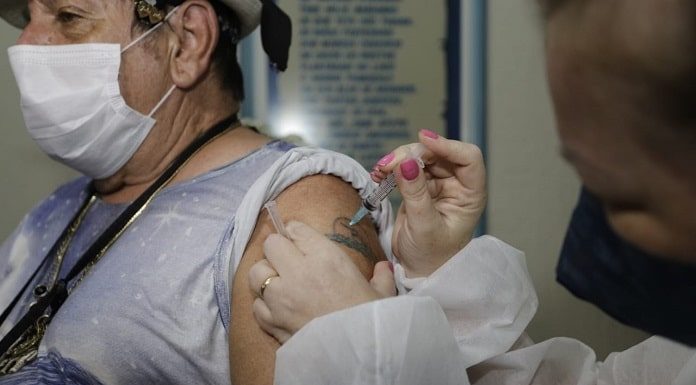 idosa usando máscara recebe dose de vacina no braço - vacinação de idosos acima de 75 anos