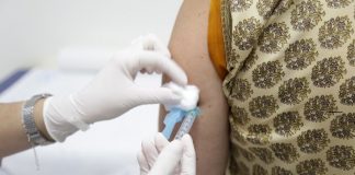 início da vacinação de covid em sc previsto para final de janeiro - profissional de saúde com luva dá vacina no braço de senhora