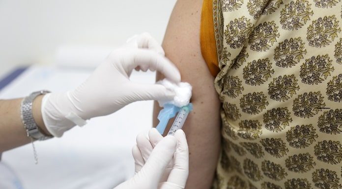 início da vacinação de covid em sc previsto para final de janeiro - profissional de saúde com luva dá vacina no braço de senhora
