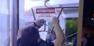 fiscal coloca adesivo em vidro indicando estabelecimento interditado em balneário camboriú; boates foram fiscalizadas