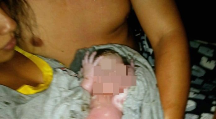 mãe dá à luz na sc 401 - a foto mostra ela com o bebê embrulhado no colo, com rosto censurado