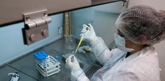 pesquisadora manipula amostras para sequenciar genoma do coronavírus, ela usa equipamentos de proteção e uma seringa especial