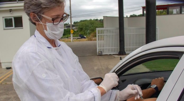 plano de vacinação de coronavírus em são josé preve drive-thru; mulher da vacina em braço de motorista dentro de carro