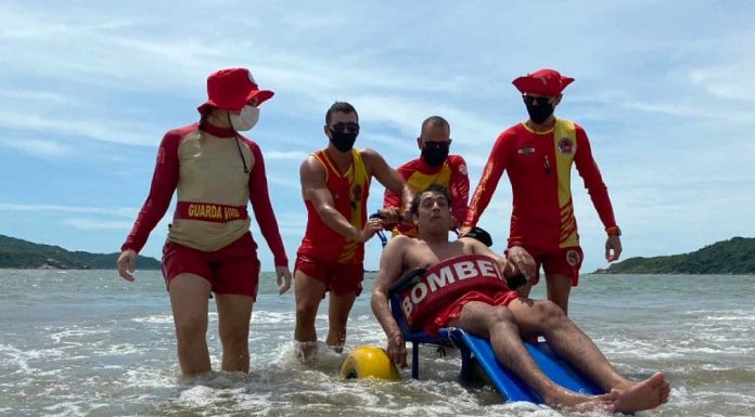 acessibilidade praias Palhoça - quatro guarda-vidas e um homem com deficiência física dentro do mar