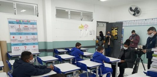 Aulas em São José retornam em 22 de fevereiro com diagnóstico dos estudantes alguns alunos usando máscaras em carteiras com outros adultos de máscara na sala - aulas em são josé retornam em 22 de fevereiro