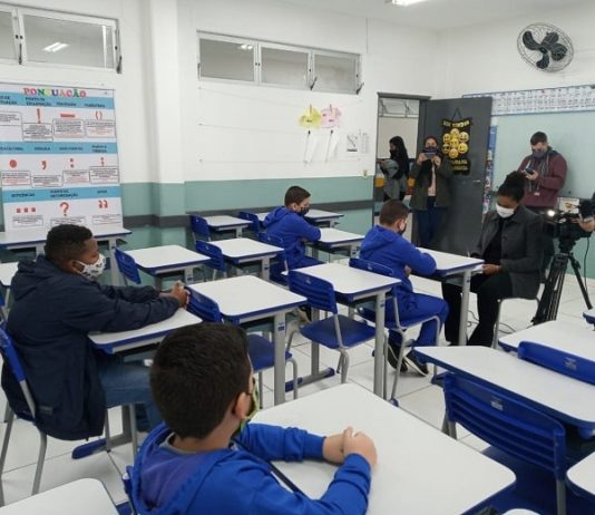 alguns alunos usando máscaras em carteiras com outros adultos de máscara na sala - aulas em são josé retornam em 22 de fevereiro