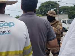 funcionários da comcap em greve vistos de costas com policial de máscara à frente - sintrasem matem a greve
