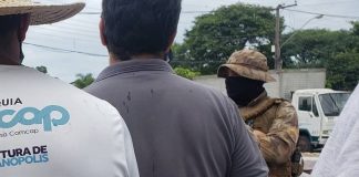 funcionários da comcap em greve vistos de costas com policial de máscara à frente - sintrasem matem a greve