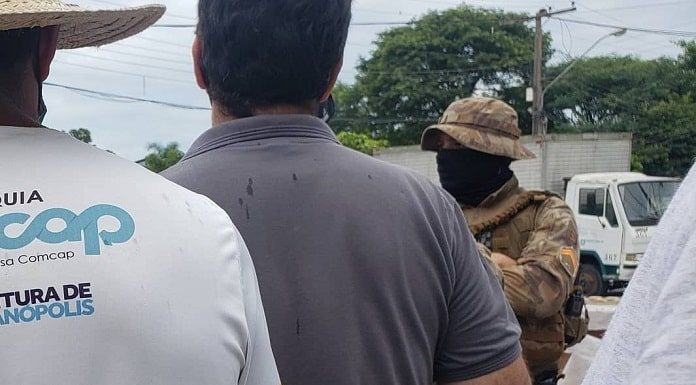 funcionários da comcap em greve vistos de costas com policial de máscara à frente - sintrasem matem a greve