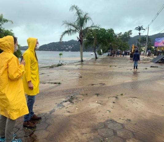 Laudo do IMA mostra que pontos da Lagoa estão com mais coliformes fecais técnicos do ima usando capas de chuva olham para avenida das rendeiras tomada por lama - análise do órgão mostra que lagoa está com mais coliformes fecais