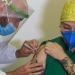 enfermeiro aplica injeção no braço da mulher