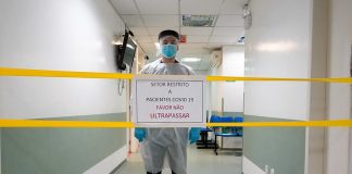 profissional de saúde atrás de placa restringindo corredor de hospital - lockdown no final de semana em santa catarina