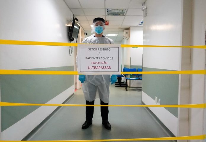 profissional de saúde atrás de placa restringindo corredor de hospital - lockdown no final de semana em santa catarina
