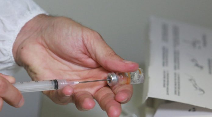 profissional de saúde retira dose de vacina de ampola com agulha, close nas mãos - Governo de SC mantém meta de vacinar 2,8 milhões dos prioritários em 2021