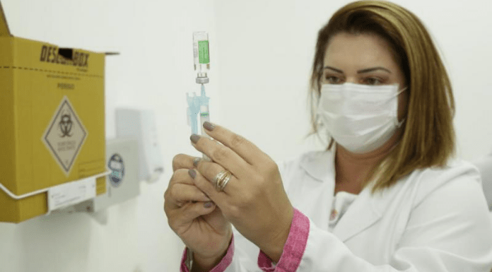 profissional de saúde, entre as pessoas que foram vacinadas contra covid em floripa, segura seringa; ela está em um consultório