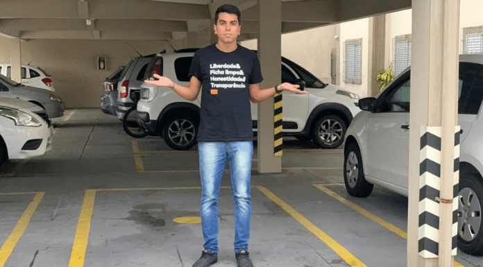 Vereador Cryslan do partido NOVO, parado no meio da garagem com os braços abertos
