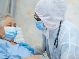 Idosos: Médica com equipamentos de proteção contra Covid-19 na casa de uma senhora idosa que está deitada e de máscara