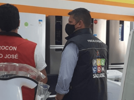 Procon/SJ orienta lojistas sobre direito do consumidor em caso de produto com defeito Dois agentes do Procon de São José de costas, realizando fiscalização em um estabelecimento do município