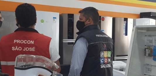 Procon/SJ orienta lojistas sobre direito do consumidor em caso de produto com defeito Dois agentes do Procon de São José de costas, realizando fiscalização em um estabelecimento do município
