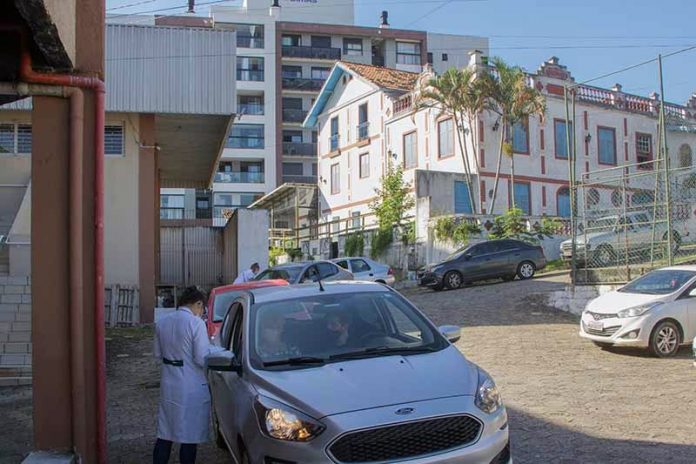 drive-thru de vacinação no primeiro de junho com profissional de saúde ao lado de carro para vacinar idosos em são josé