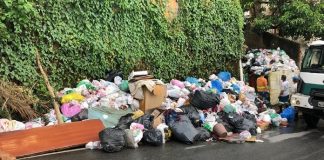 montanha de sacos de lixo acumulada em calçada com dois funcionários ao lado - Coleta seletiva será retomada na quarta em Florianópolis