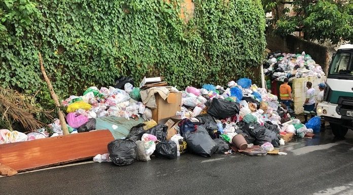 montanha de sacos de lixo acumulada em calçada com dois funcionários ao lado - Coleta seletiva será retomada na quarta em Florianópolis