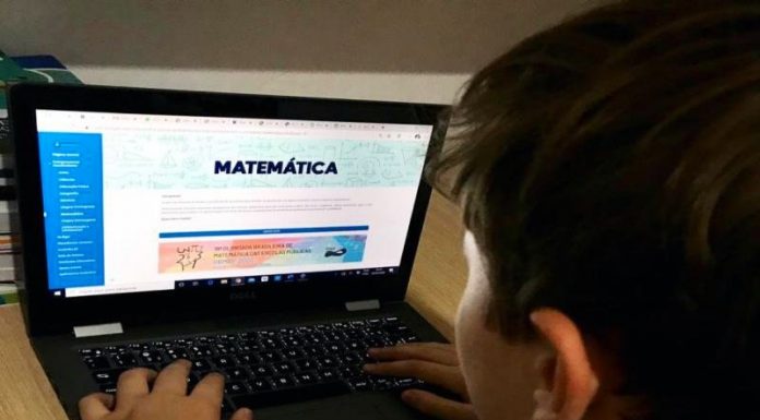 Ano letivo na rede municipal de Florianópolis começa com aulas online - garoto visto de costas no notebook com tema de matemática na tela