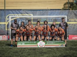 mulheres postadas para foto do time do atlético catarinense; todas sorridentes na frente do gol e com placa no chão à frente