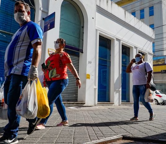 homem e duas mulheres usando máscaras caminham com sacolas pelo centro de florianópolis - comércio catarinense cresceu. apesar da pandemia