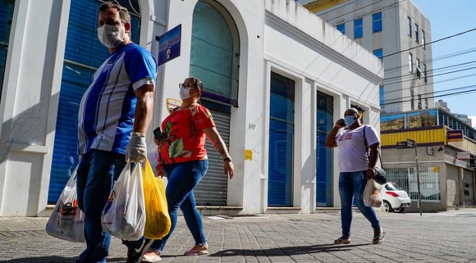 homem e duas mulheres usando máscaras caminham com sacolas pelo centro de florianópolis - comércio catarinense cresceu. apesar da pandemia