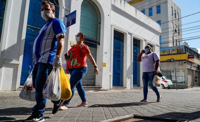 homem e duas mulheres usando máscaras caminham com sacolas pelo centro de florianópolis - comércio catarinense cresceu. apesar da pandemia