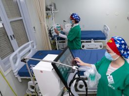 duas profissionais de saúde mexem em equipamentos de uti com leitos vazios - governo suspende consultas e exames para desafogar hospitais