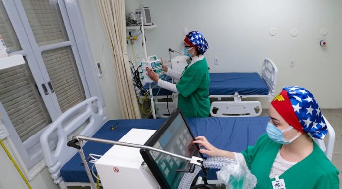 duas profissionais de saúde mexem em equipamentos de uti com leitos vazios - governo suspende consultas e exames para desafogar hospitais