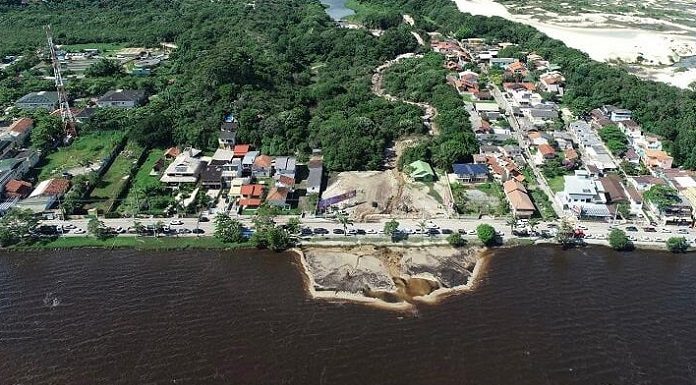 Foto de cima da Lagoa da Conceição. Em baixo uma aguá escurecida, em cima área verde com casas e terrenos dividindo espaço. Dos 9 pontos de coleta do IMA, 1 não é próprio para banho na Lagoa.