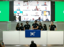 Seis representantes da Intelbras em evento que marca estreia da empresa na bolsa de valores. Ao fundo três telas, a do meio com participantes do evento em chamada de vídeo e as outras duas com cor verde e "Intelbras" escrito em branco.