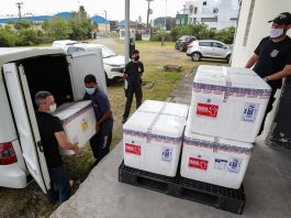 Santa Catarina recebe 59,5 mil doses da vacina Oxford-AstraZeneca homens retiraram de carro as caixas de isopor contendo doses da vacina Oxford observados por um policial federal em área externa
