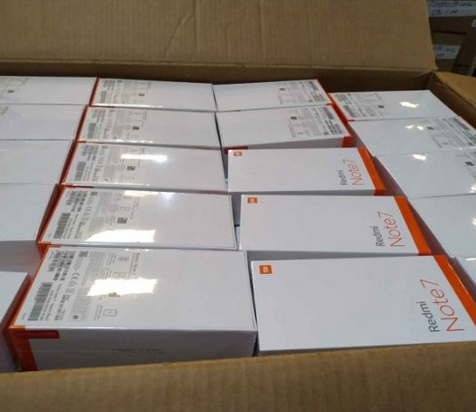 Caixa de papelão pardo com várias caixas brancas de celulares que farão parte do leilão da Receita Federal