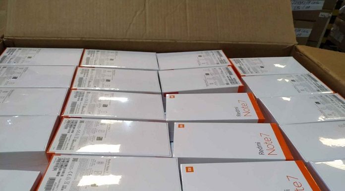 Caixa de papelão pardo com várias caixas brancas de celulares que farão parte do leilão da Receita Federal