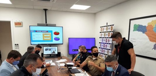 grupo de policiais e membros do gaeco em mesa grande dentro de sala de coordenação da operação maserati