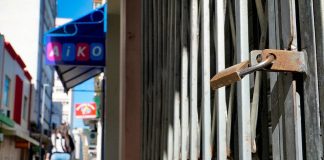 cadeado fechando loja no centro de florianópolis e mulher passando ao fundo em calçadão - orgãos recomendam lockdown em sc