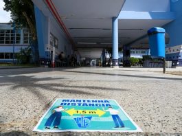 cartaz colado no chão informa sobre necessidade de alunos manterem distanciamento nas escolas para o retorno às aulas; chão do IEE